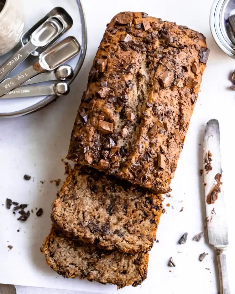 Sliced banana bread with knife and measuring spoons