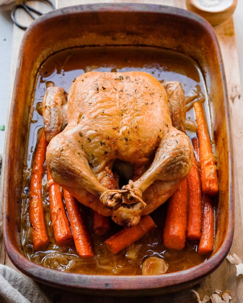 Roasted chicken with carrots in a roasting pan