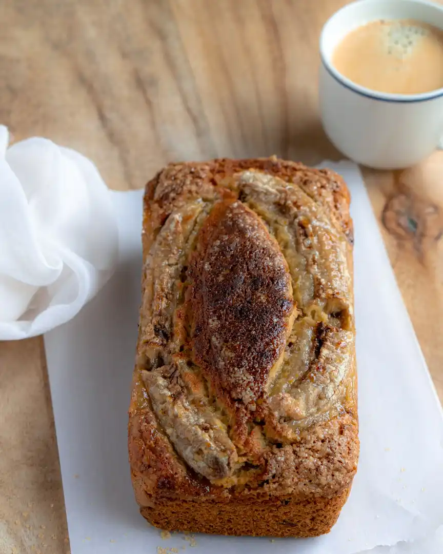 A loaf of date orange banana bread with a cup of coffee