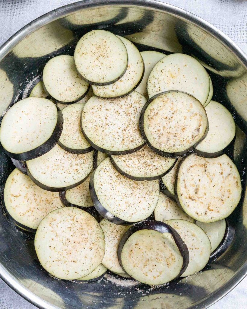 Eggplant sliced into rounds in a bowl.