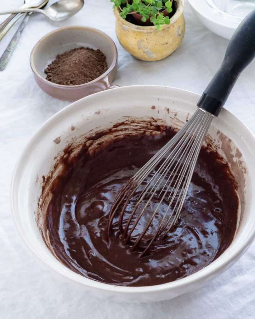 A bowl of chocolate cake batter with a whisk