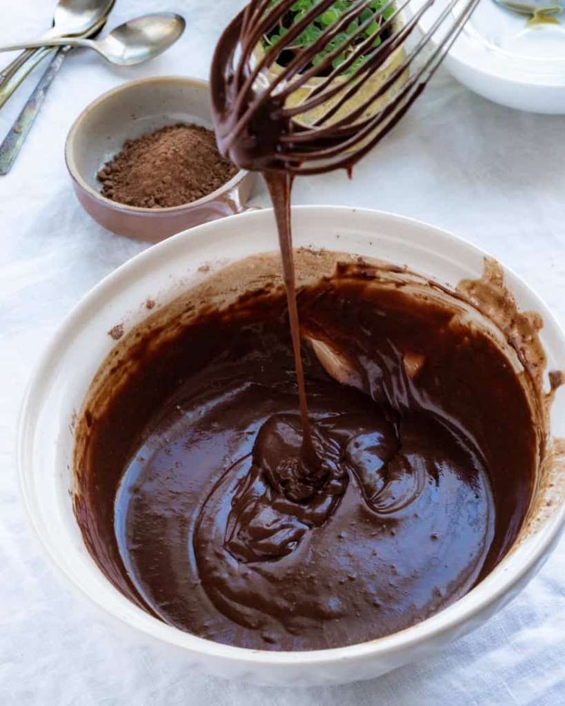 Chocolate cake batter falling from a whisk.