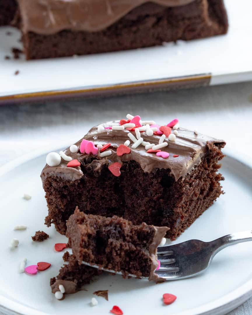 Chocolate cake with heart colored sprinkles and a piece of cake on a fork.