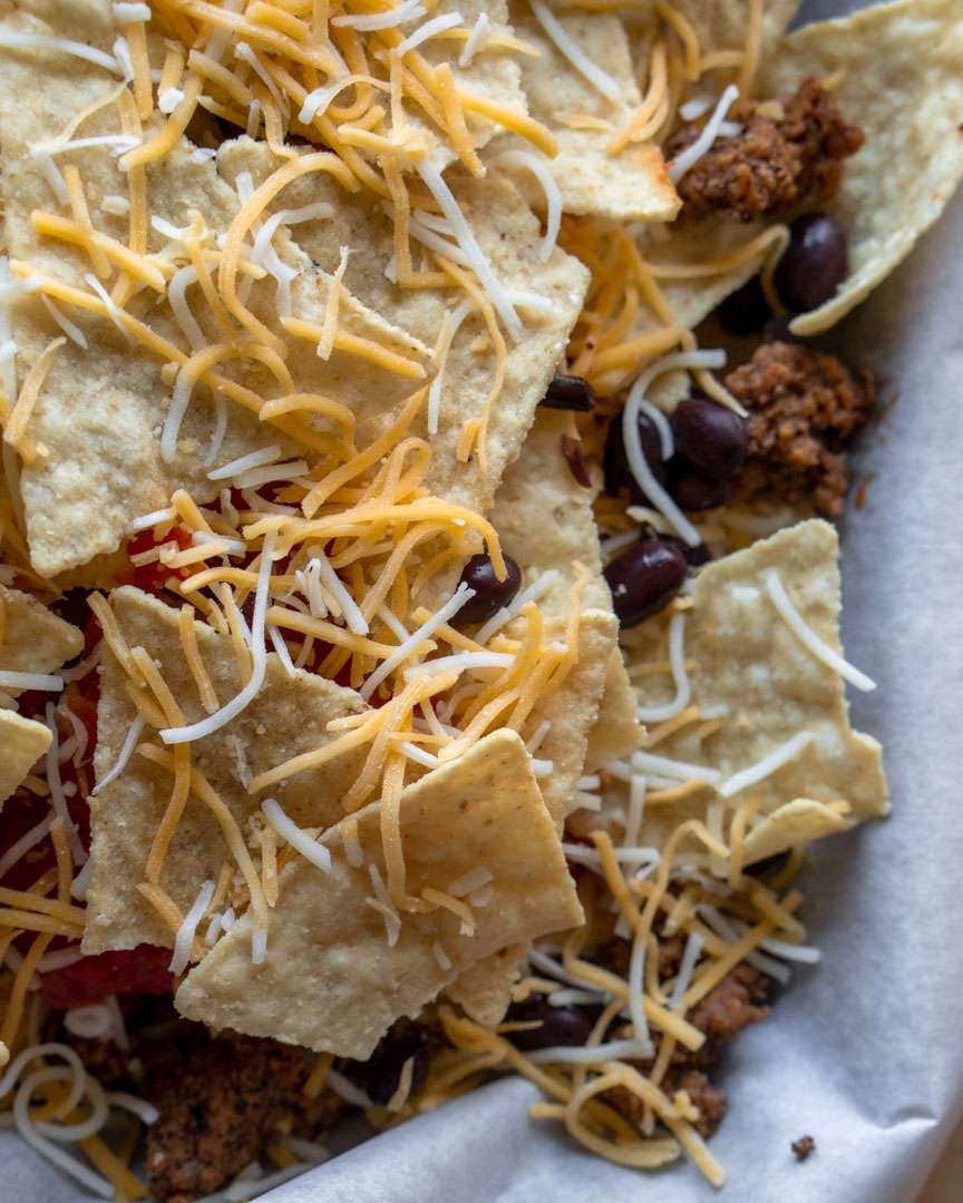 Shredded Cheese on nacho chips layered with beans and beef
