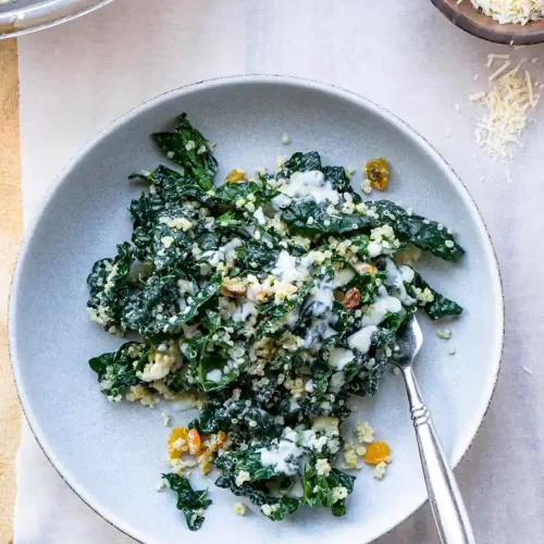 Plate with Kale and Quinoa Salad with dressing on top and fork on the plate.