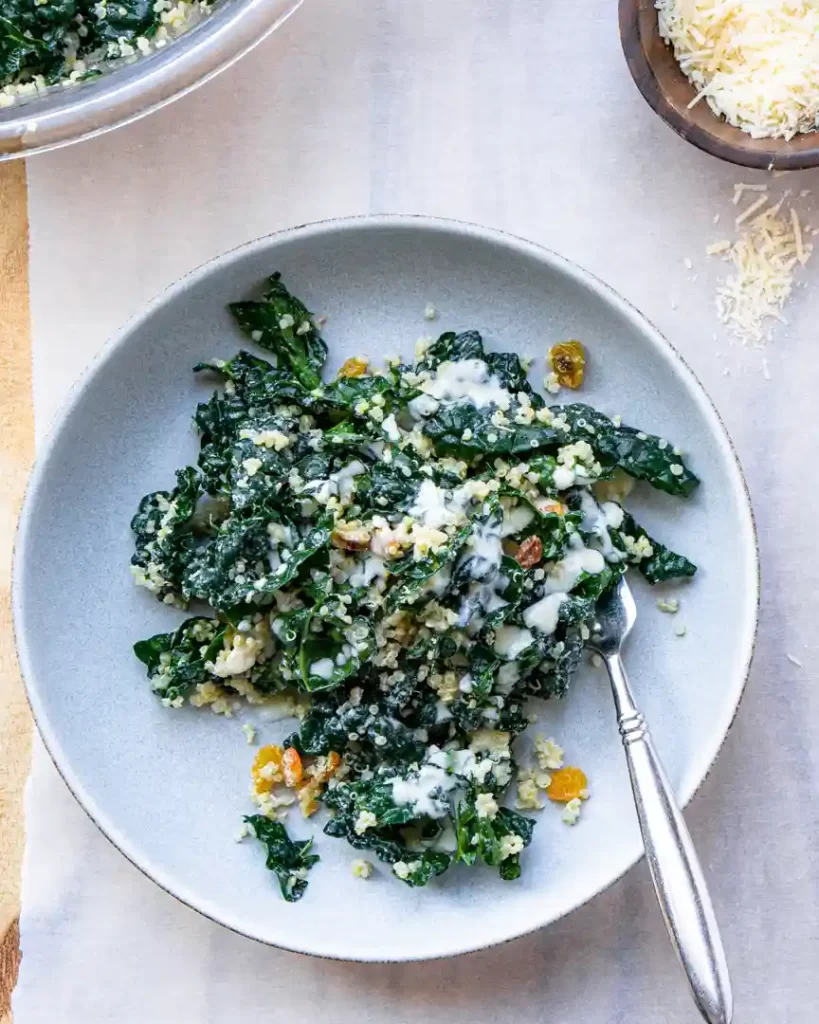 Plate with Kale and Quinoa Salad with dressing on top and fork on the plate.