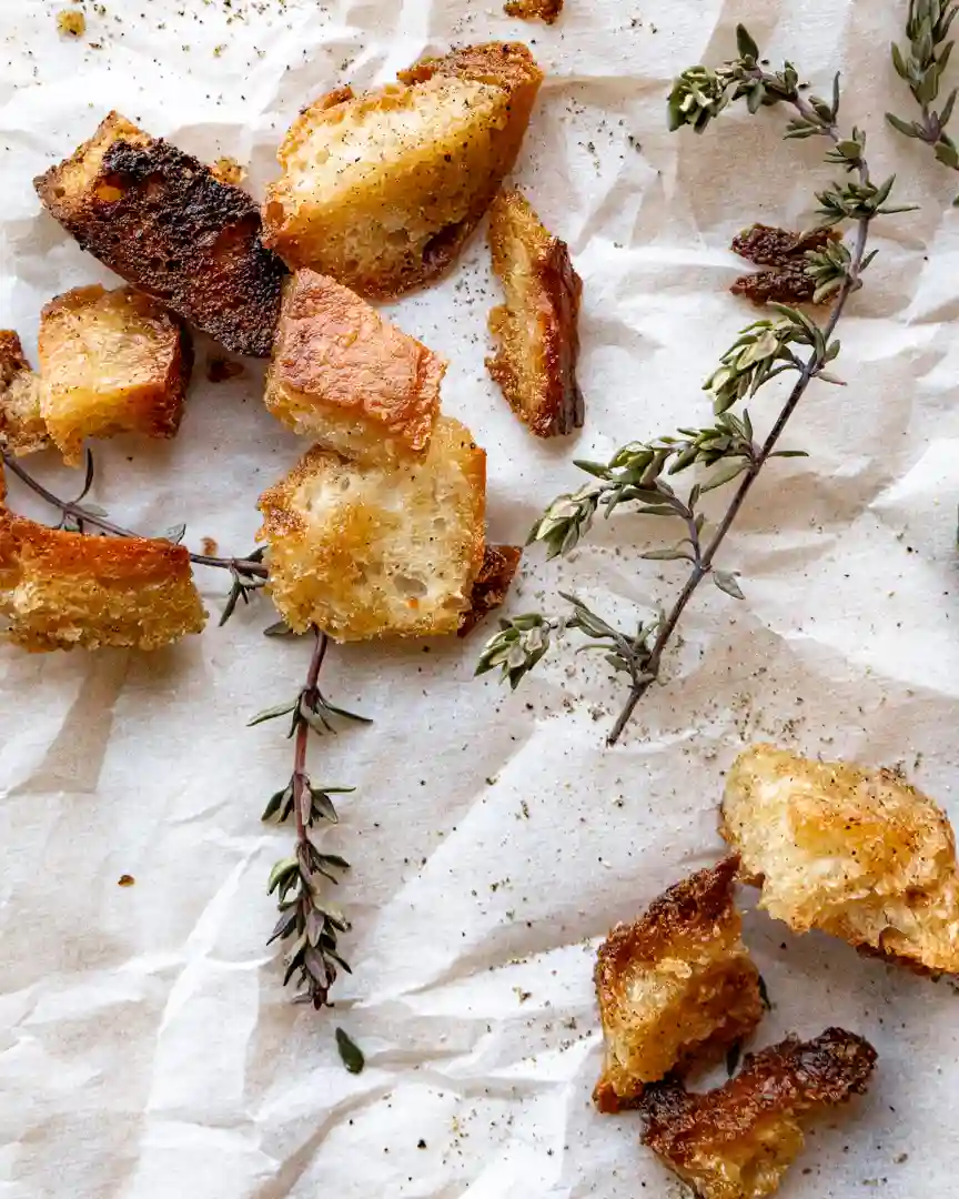 homemade croutons on parchment paper with thyme sprigs