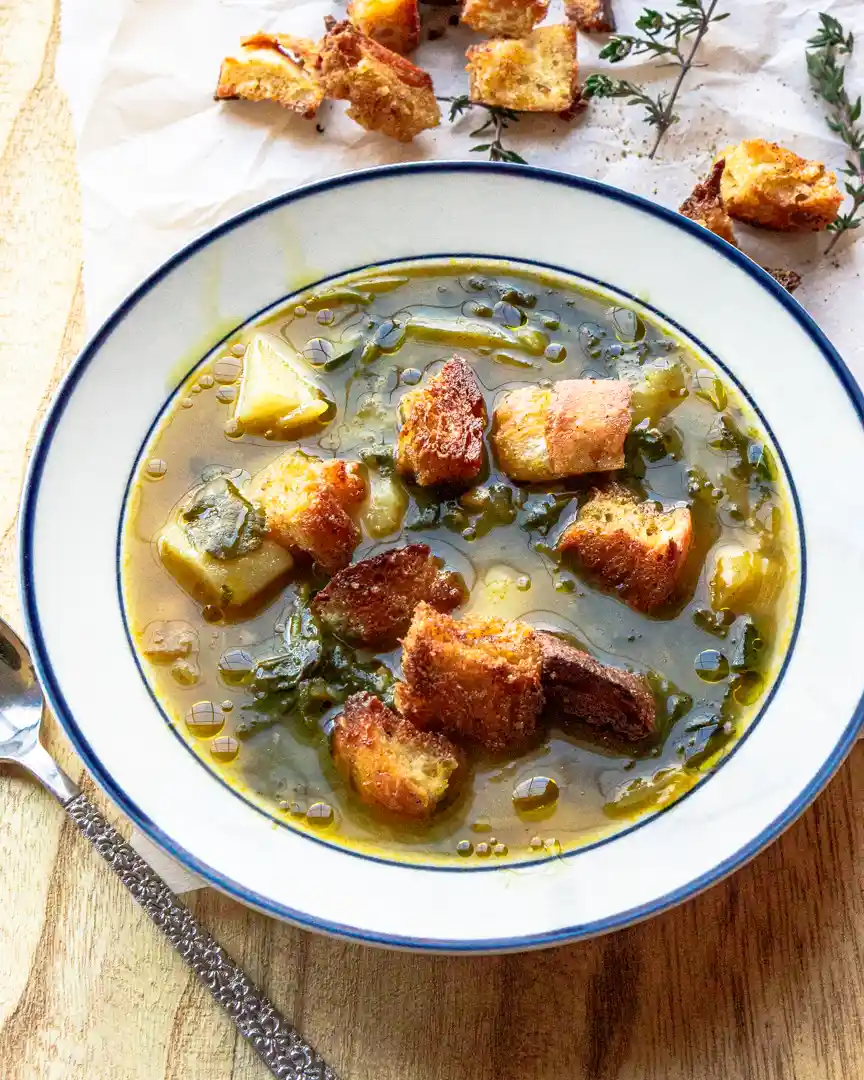 bowl of soup with croutons, potatoes and kale