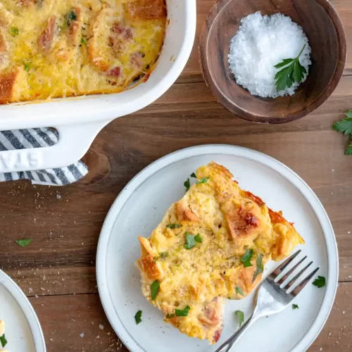 Piece of ham and cheese strata on a plate with a fork