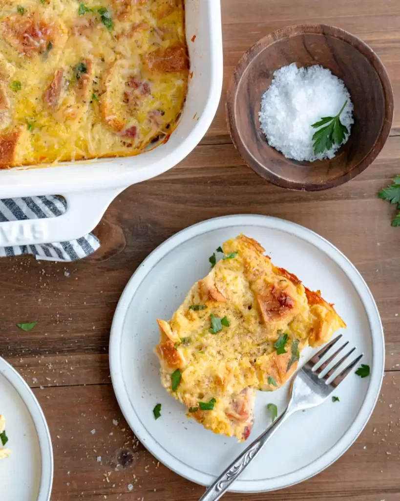 Piece of ham and cheese strata on a plate with a fork