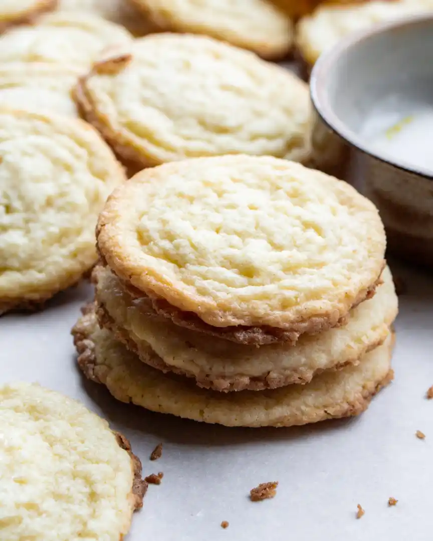 Lemon butter sugar cookies stacked with other cookies nearby