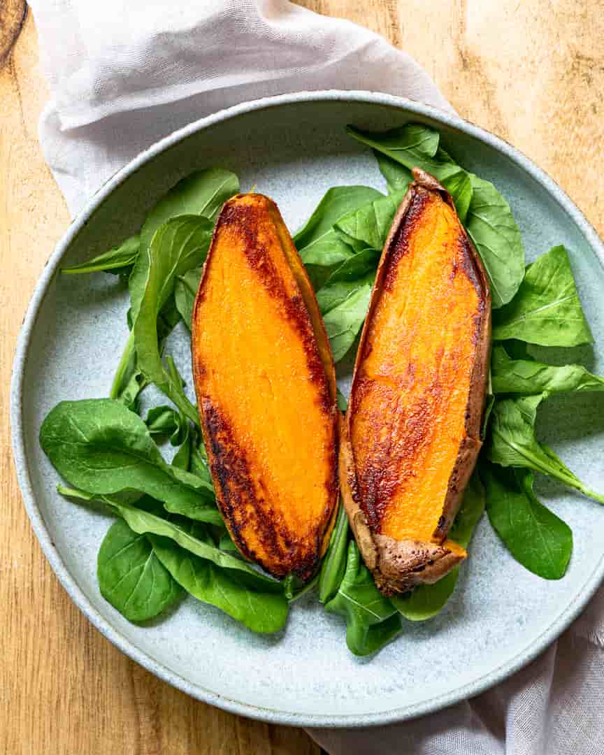 roasted sweet potato cut in half on a bed of greens