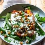 roasted sweet potato and chickpeas in a bowl topped with dressing and herbs