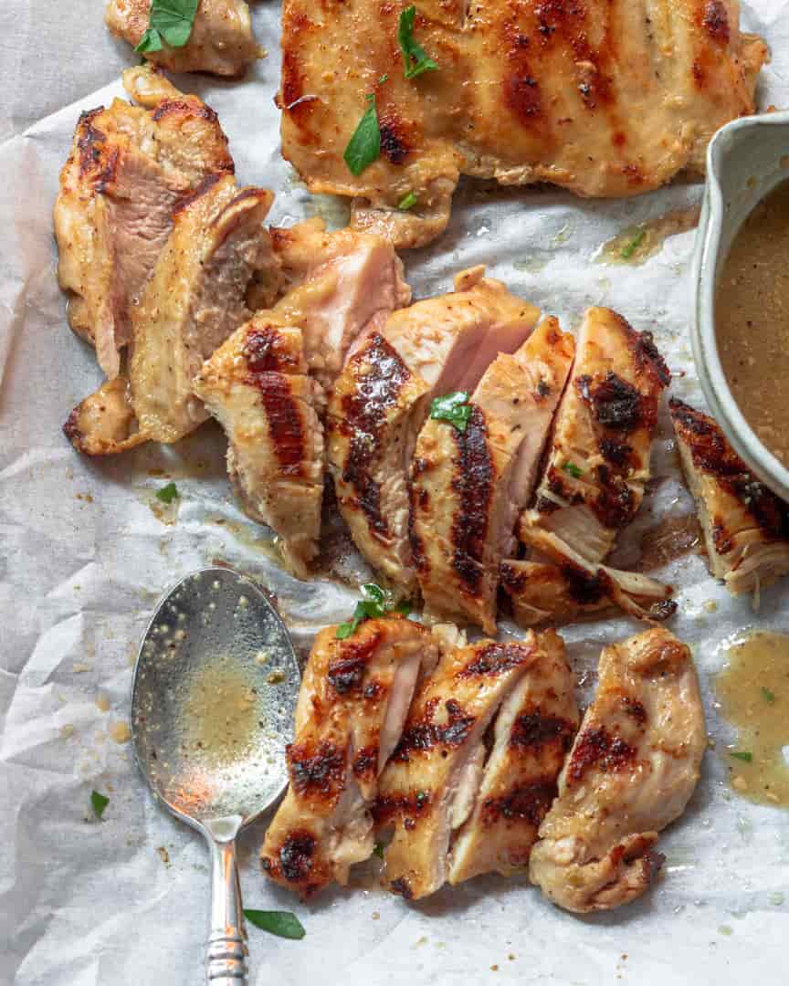 Sliced chicken marinated chicken on a tray with a spoon next to it.