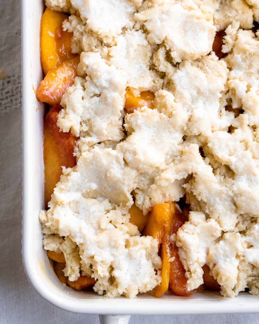 unbaked peach cobbler with dough pieces on top of peaches.