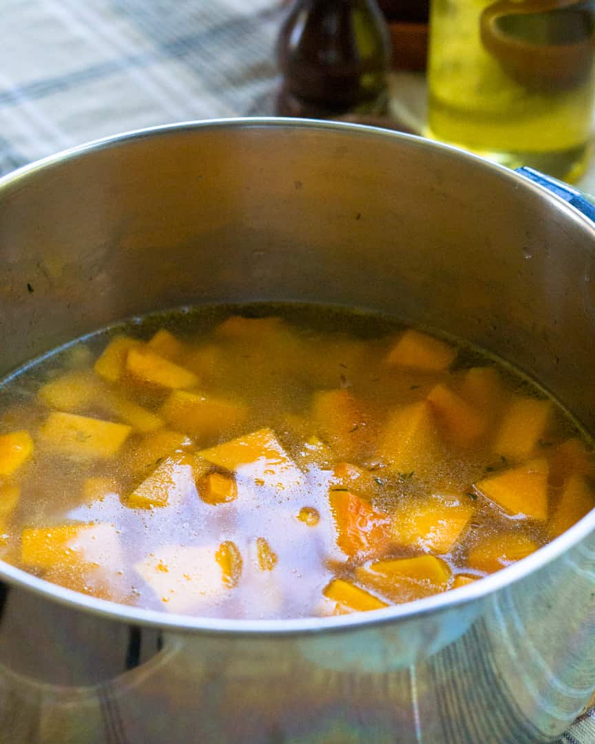 A pot of water with seasonings and butternut squash.