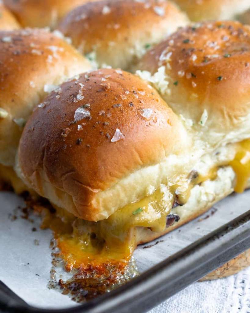 A baked roast beef slider with melted cheese.