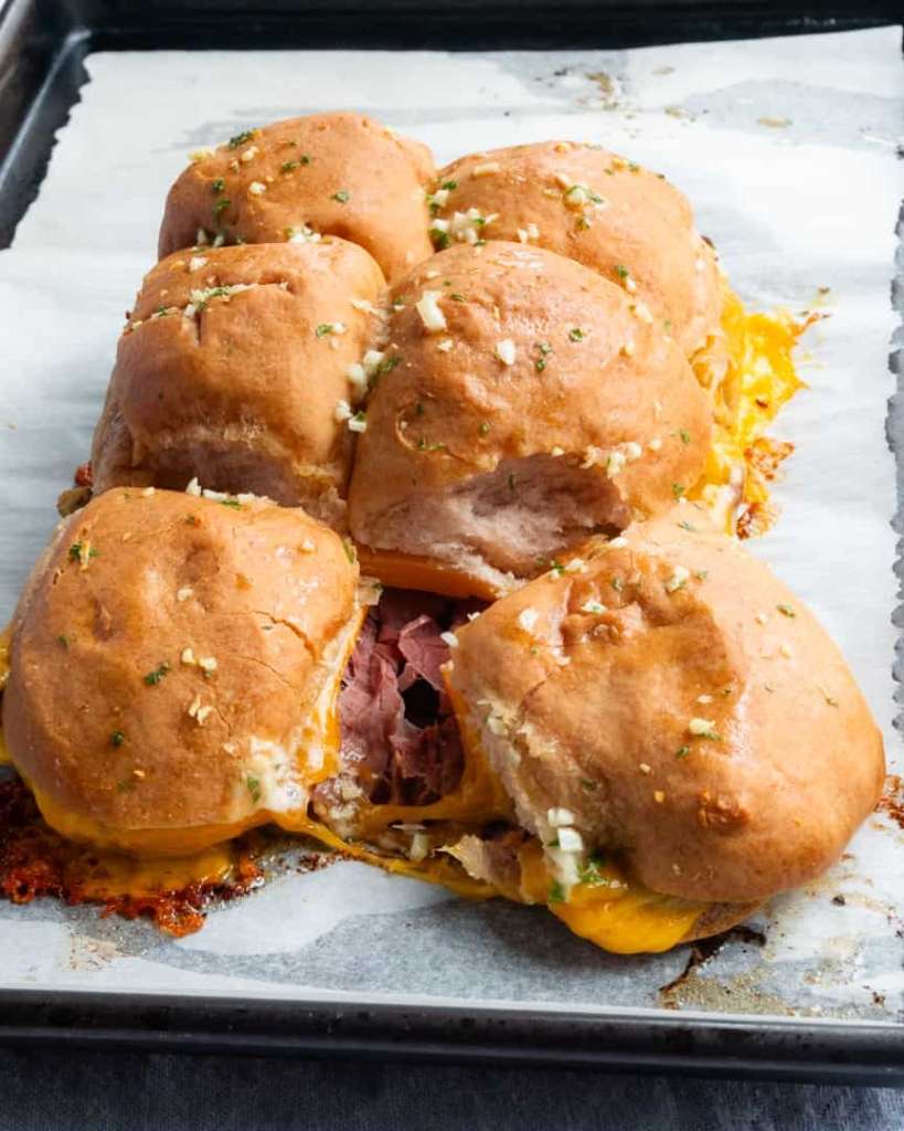 Gluten-free slider buns with two pulled away from the others and melted cheddar between the two buns.