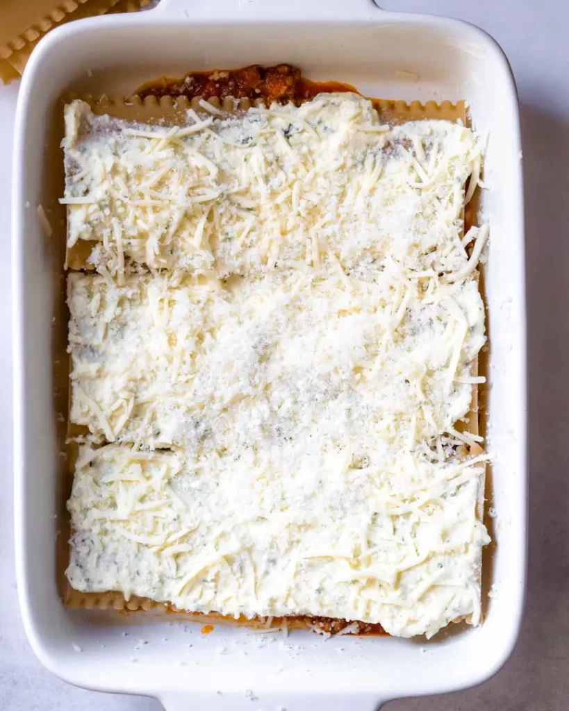 Top down view of baked lasagna noodles covered in shredded mozzarella.