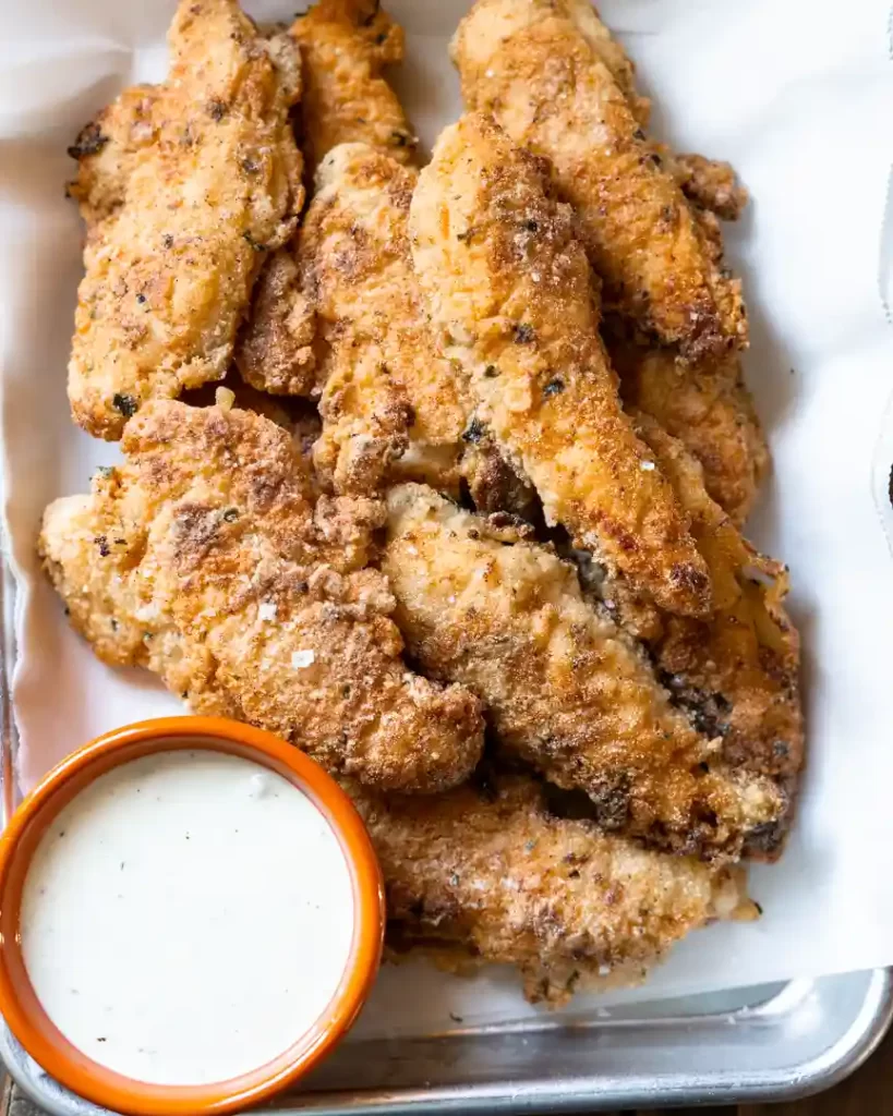 Gluten-Free Fried Buttermilk Chicken Tenders on a platter with a small bowl of ranch dressing next to it on the tray.