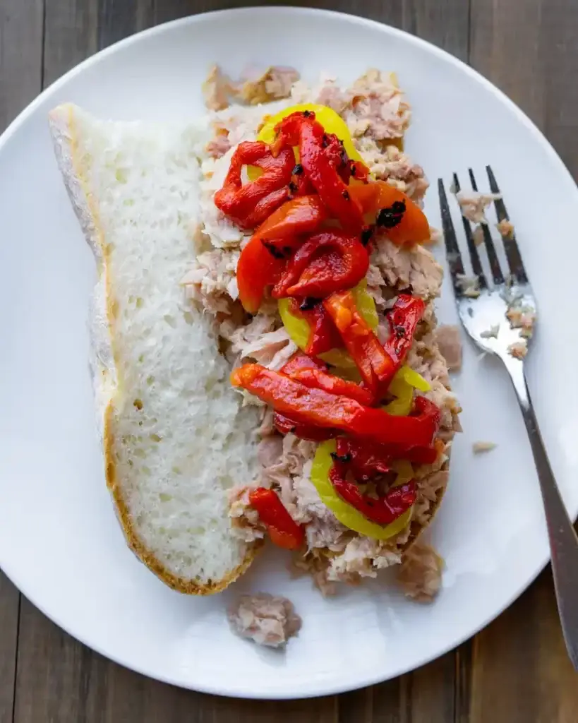 Canned tuna on a baguette topped with banana peppers and roasted red peppers.