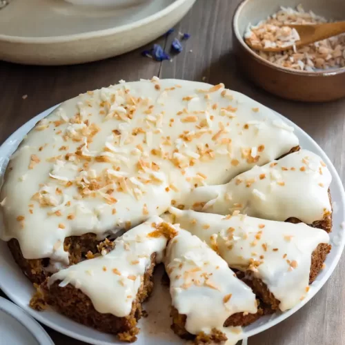 One layer gluten-free carrot cake with some cake sliced and ready to be served.