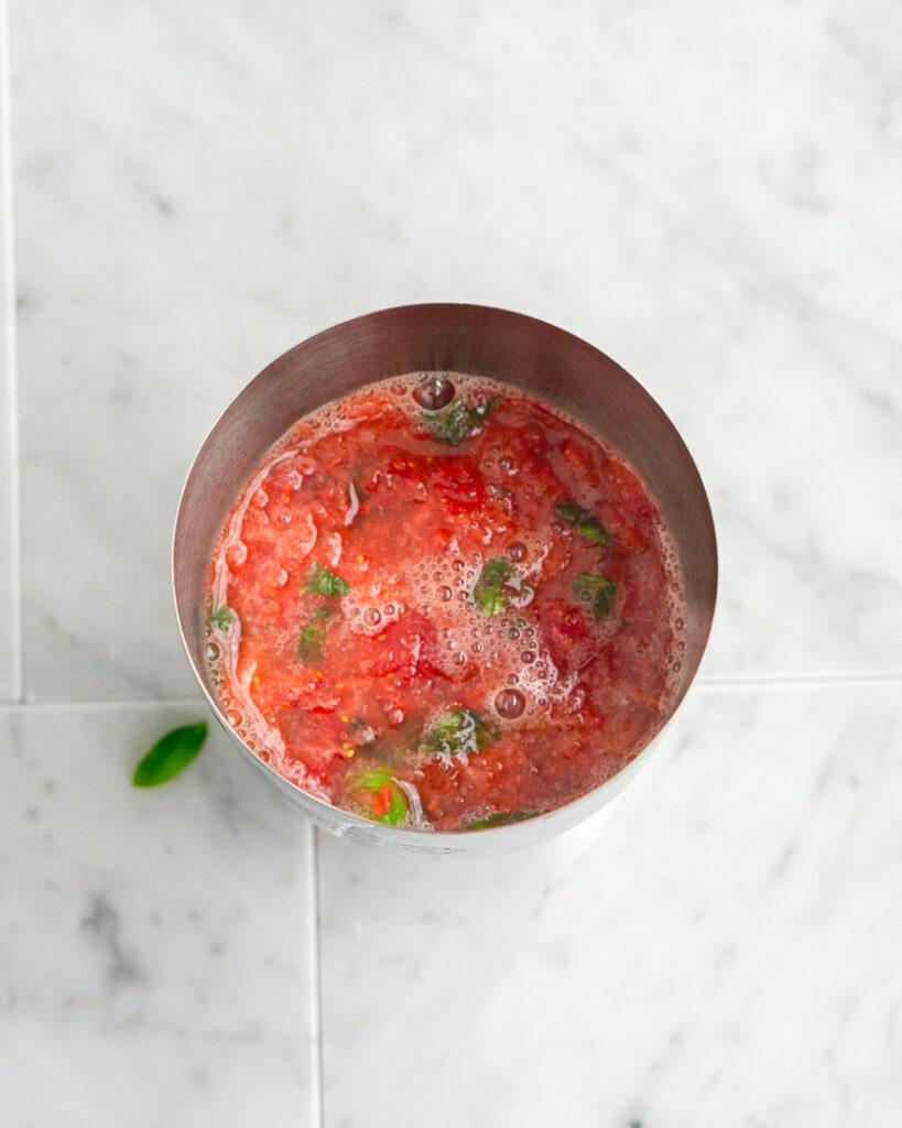 Strawberries and basil muddled into a cocktail shaker.