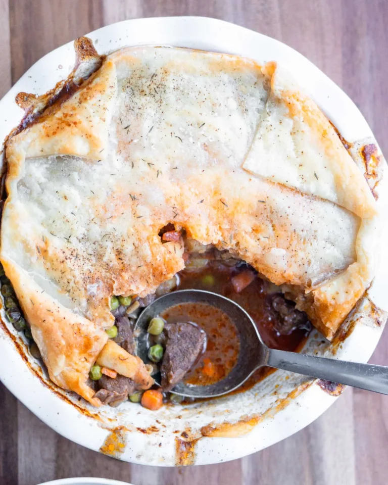 Beef pot pie with a missing scoop. There is a spoon ready to grab more sitting in the missing spot.