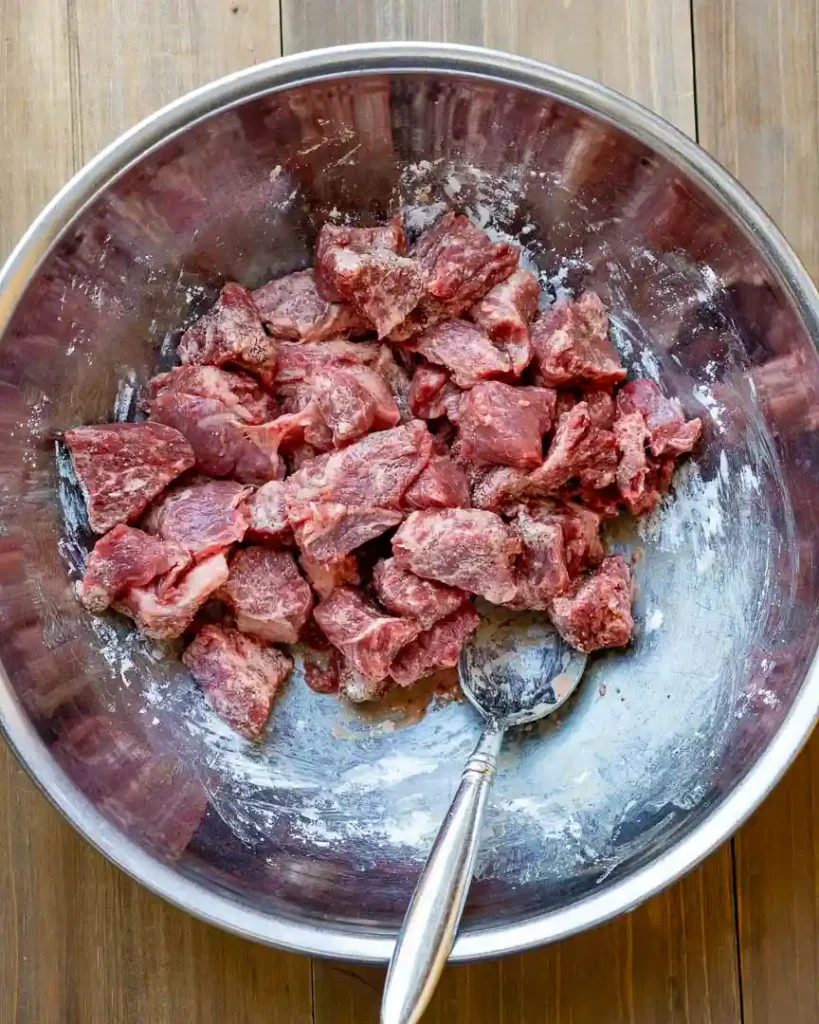 Stew meat in a bowl coated with cornstarch.