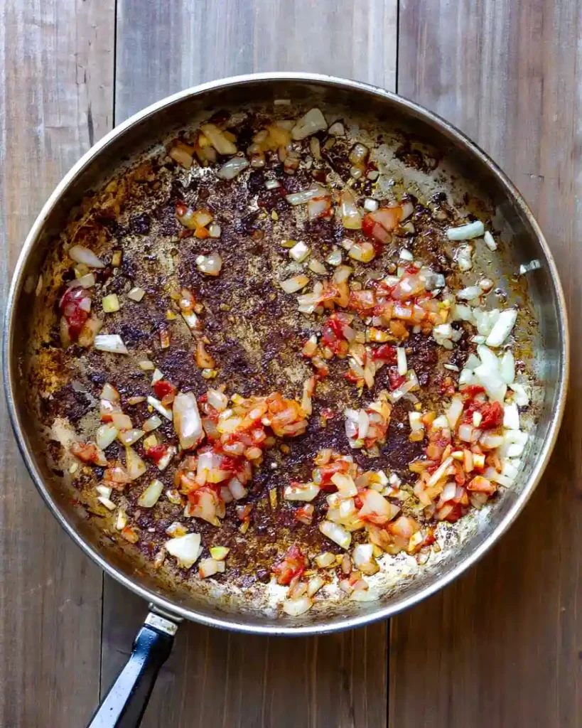 A stockpot with fried onions, garlic, and tomato paste.