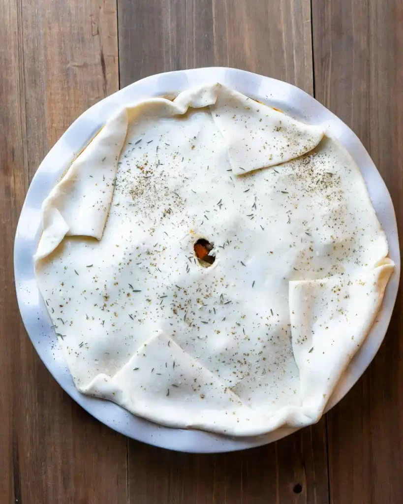Beef pot pie covered with raw puff pastry dough.