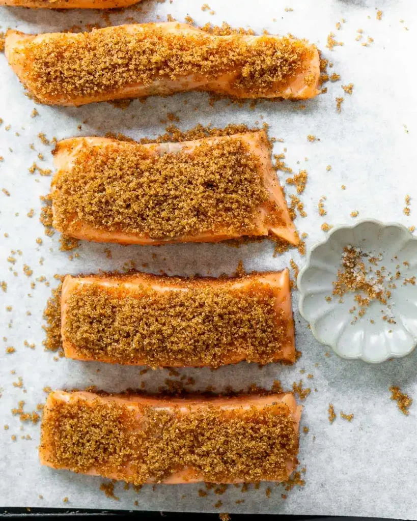 Salmon fillets with brown sugar on a baking sheet ready to be baked.