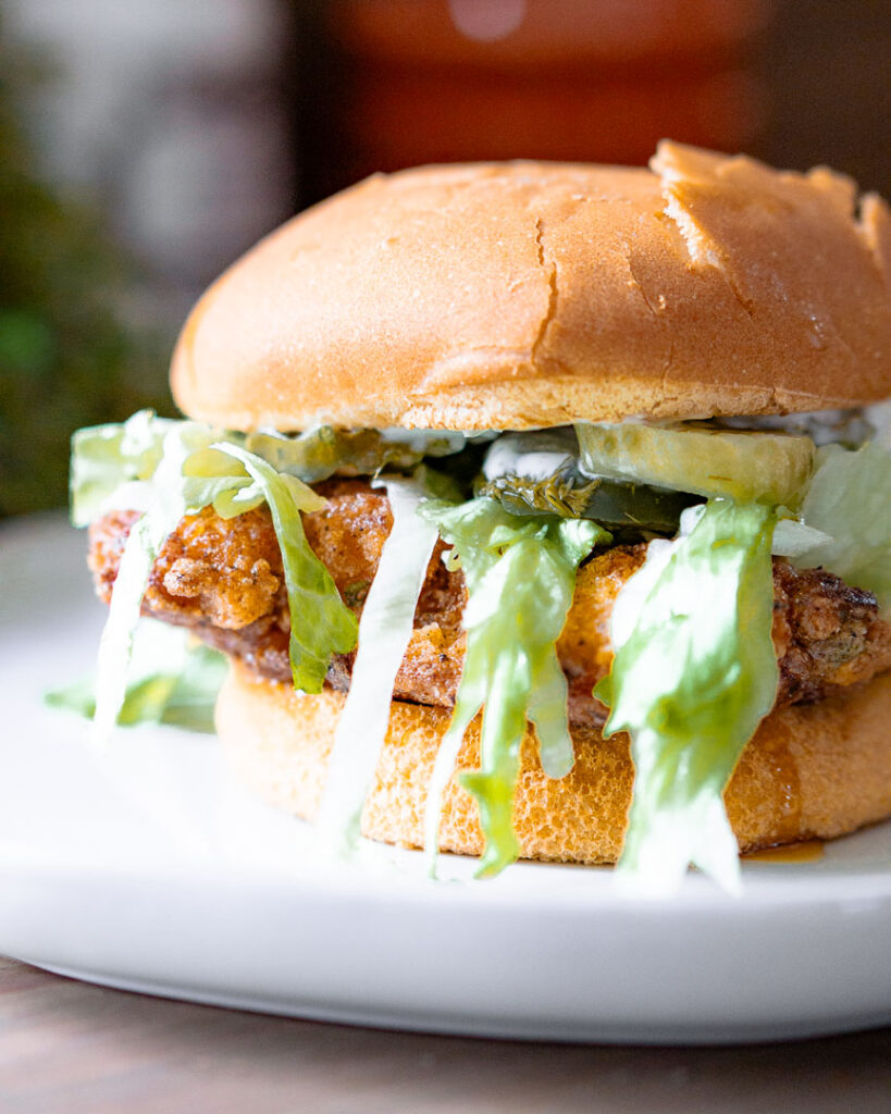 A close up of a fried chicken sandwich with lettuce peaking out the sides.