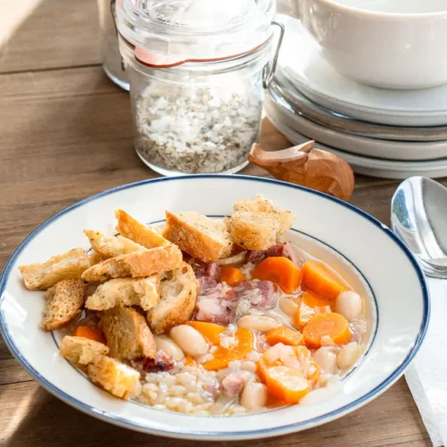 A bowl of ham hock & bean soup with croutons.