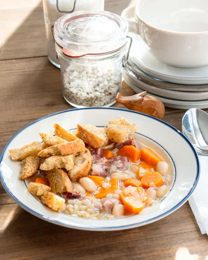 A bowl of ham hock & bean soup with croutons.