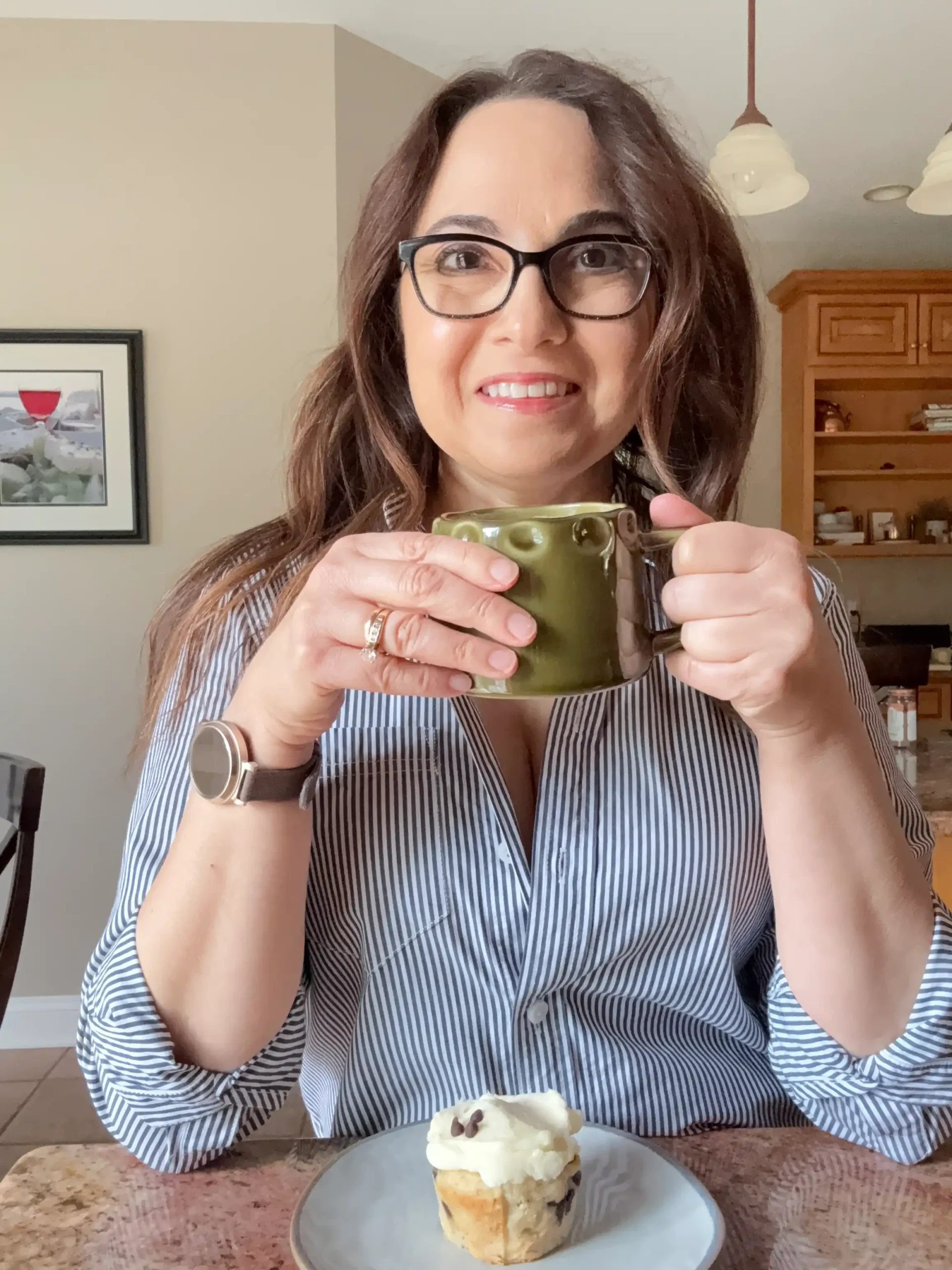 Selfie with a cup in my hand and a banana muffin on a plate in front of me.