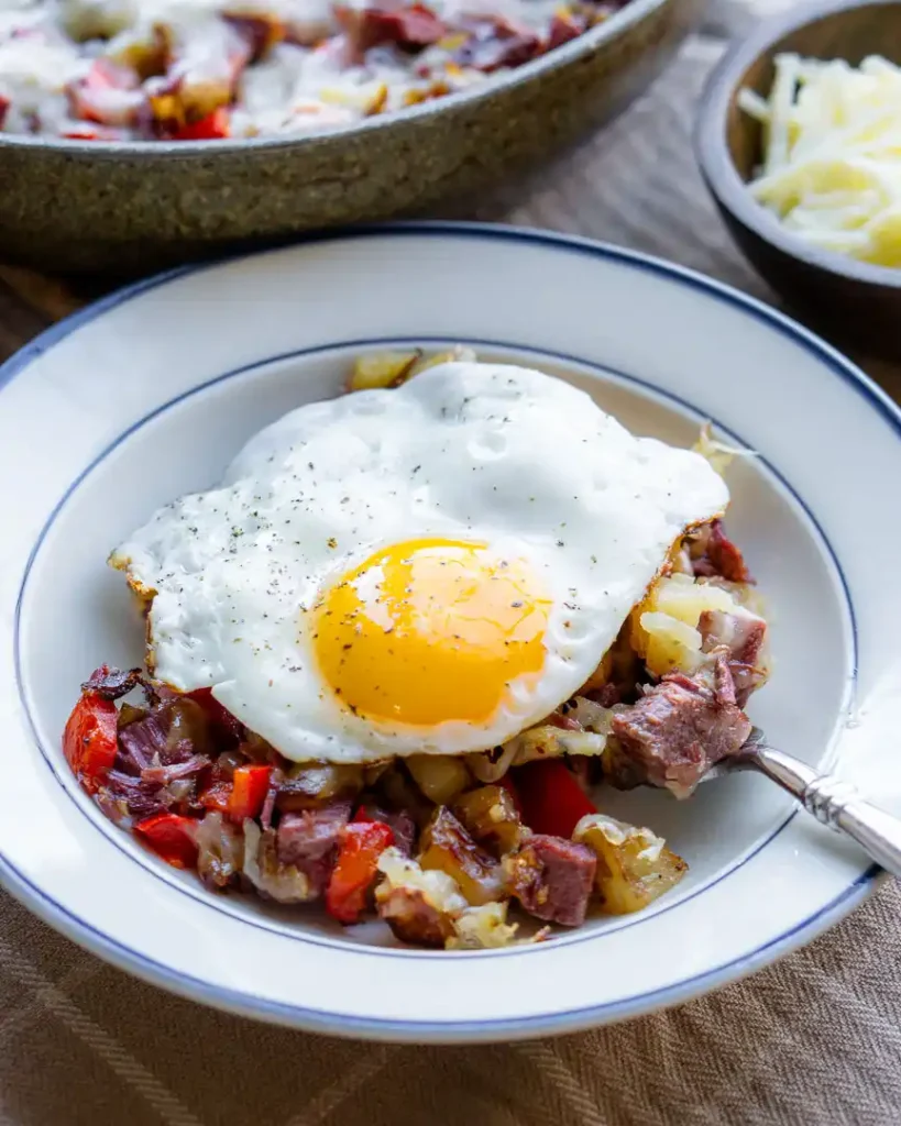 A fried egg over a bowl of corned beef hash.