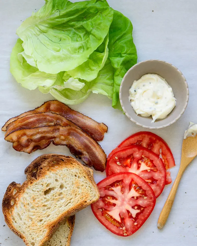 Ingredients for a blt sandwich with garlic mayo.