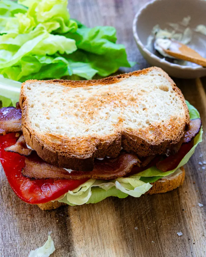 Bacon, lettuce, tomato sandwich on a wood board.