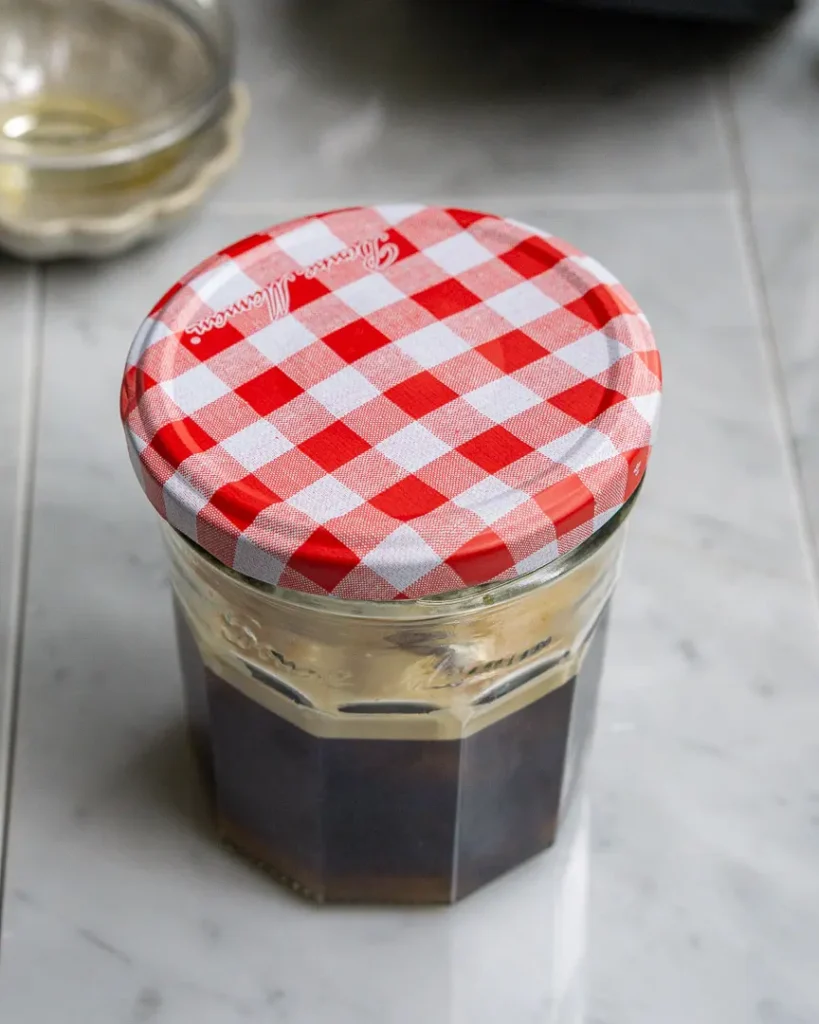A small jar filled with ice & coffee with a lid on it to be shaken.