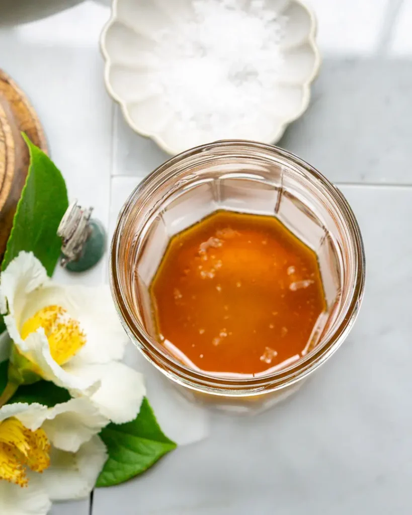 A jar with honey and a pinch of sea salt flakes in it.