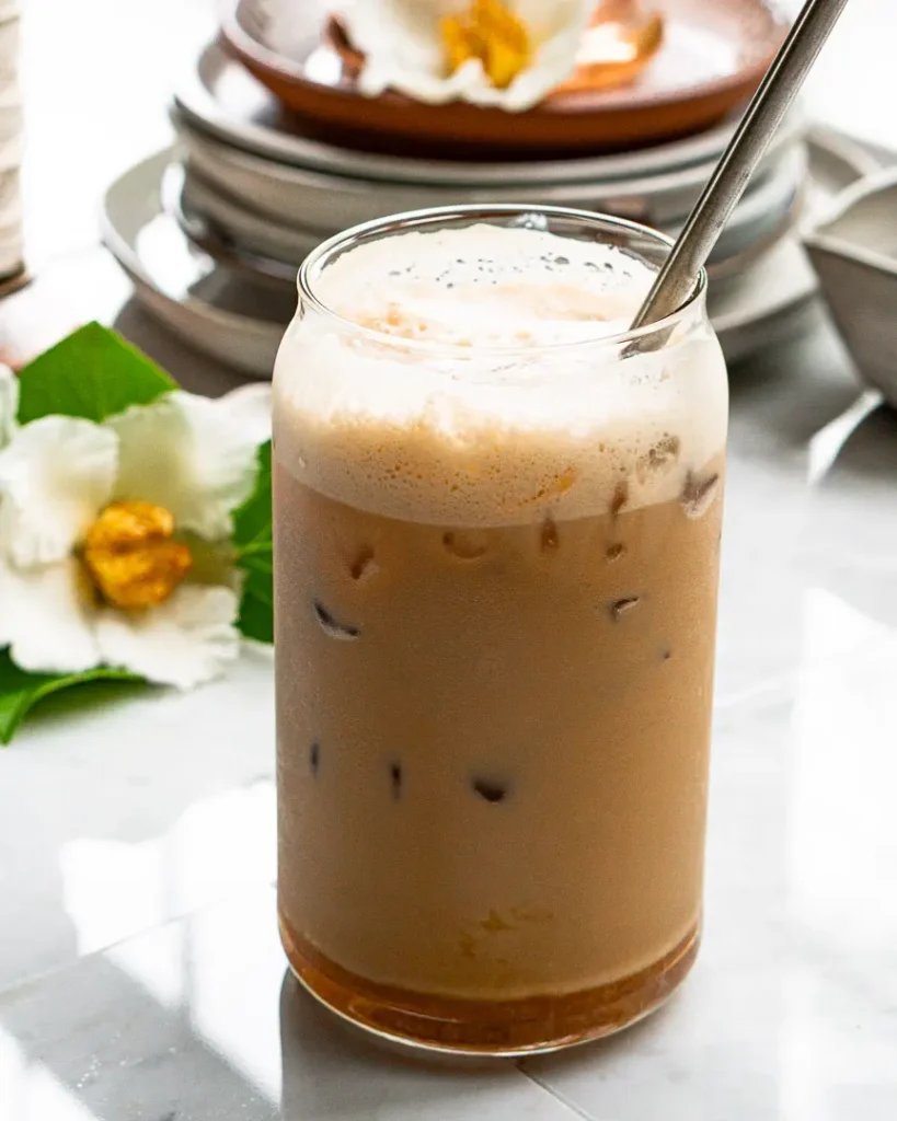 A tall glass of salted honey latte (Iced) with a metal straw sticking out of it.