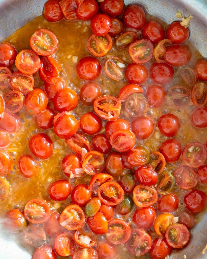 Cherry tomatoes with pasta water added to it in a sauté pan