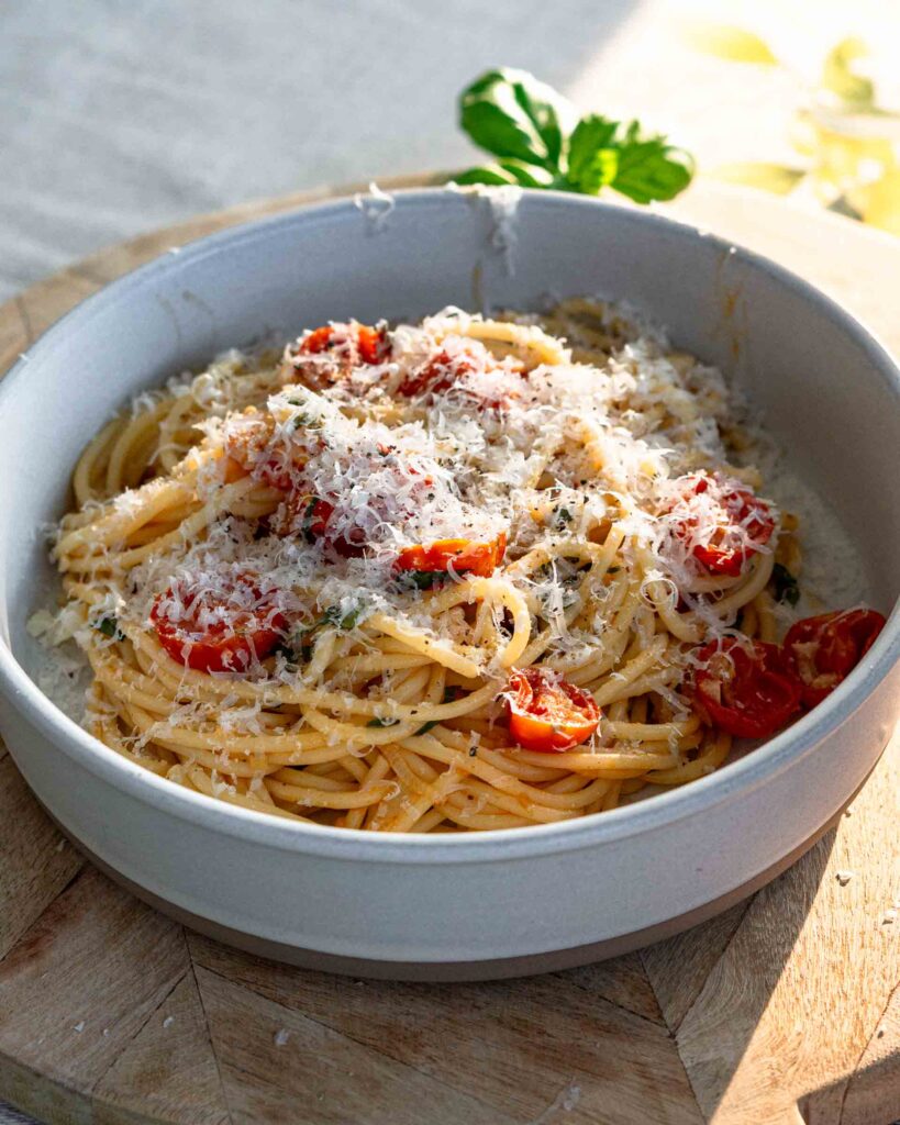 A bowl of pasta with cherry tomatoes sprinkled with parmesan cheese.