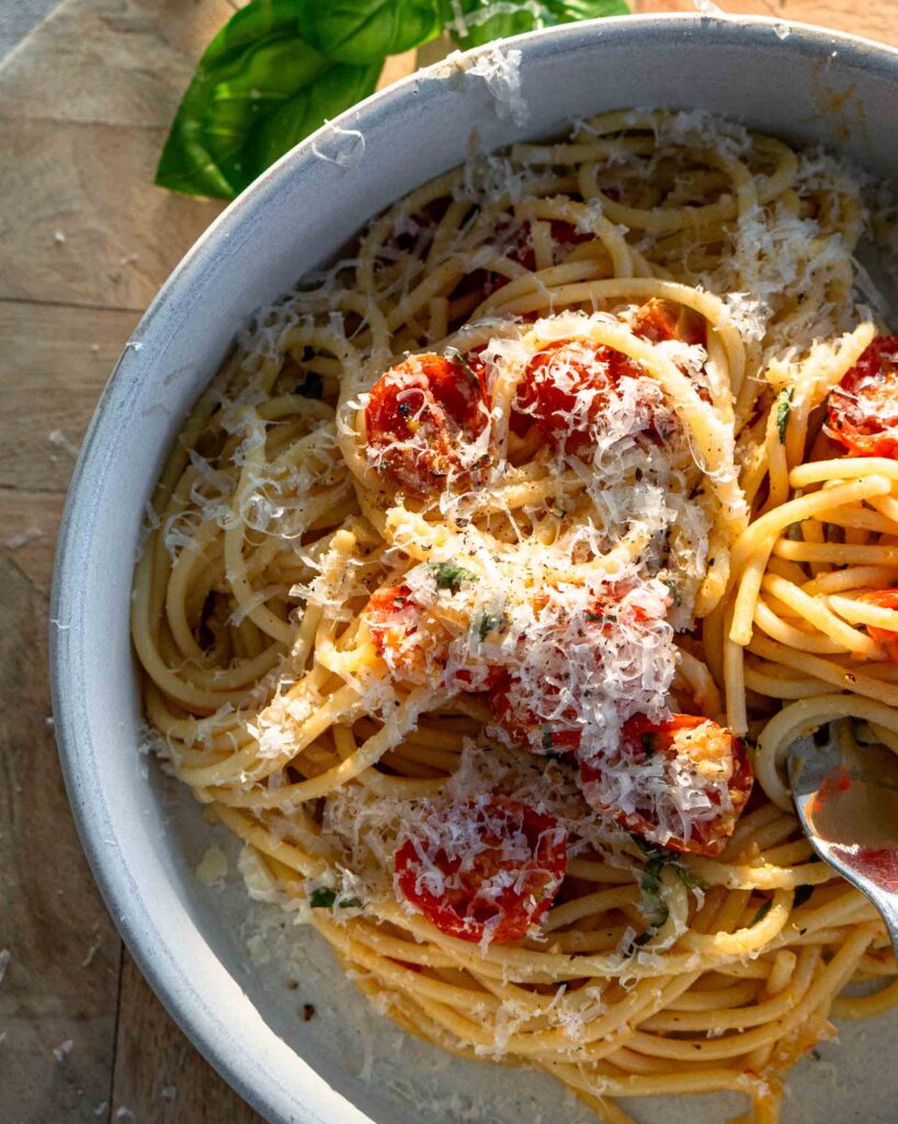 A bowl of spaghetti with grated parmesan cheese sprinkled on top.